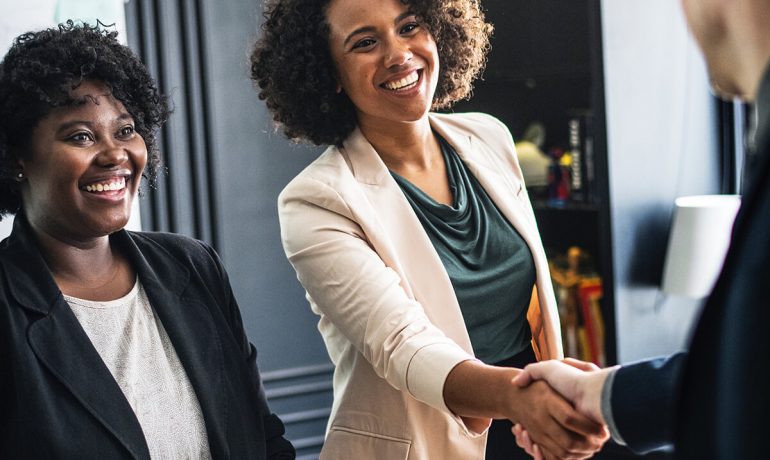 Two women ending meeting with handshake with third person